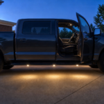Warm-white running board courtesy lights illuminating the step and ground beside a pickup truck
