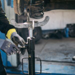 Mechanic using a spring compressor during vehicle suspension repair